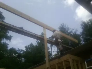 Carpenter setting a ridge beam over a new addition frame — Ice Dam Removal by Roofing Brothers in Olympia