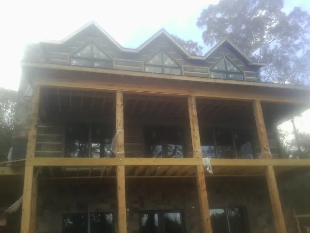 Dormers and porch framing on a large log home under construction — Roof Coating work by our crew in Olympia